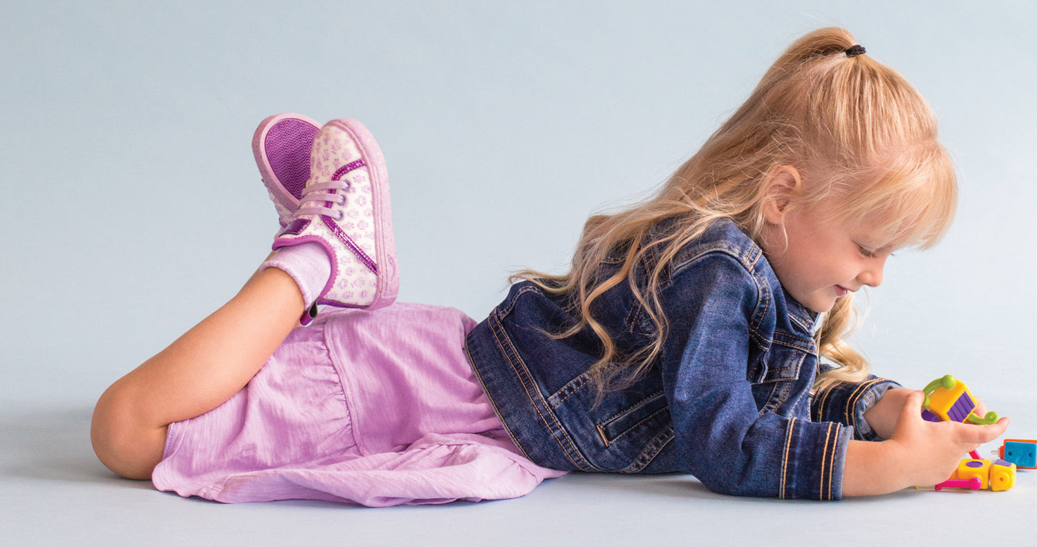 Girl laying down and playing while wearing Kazoom Purple Robot Shoes